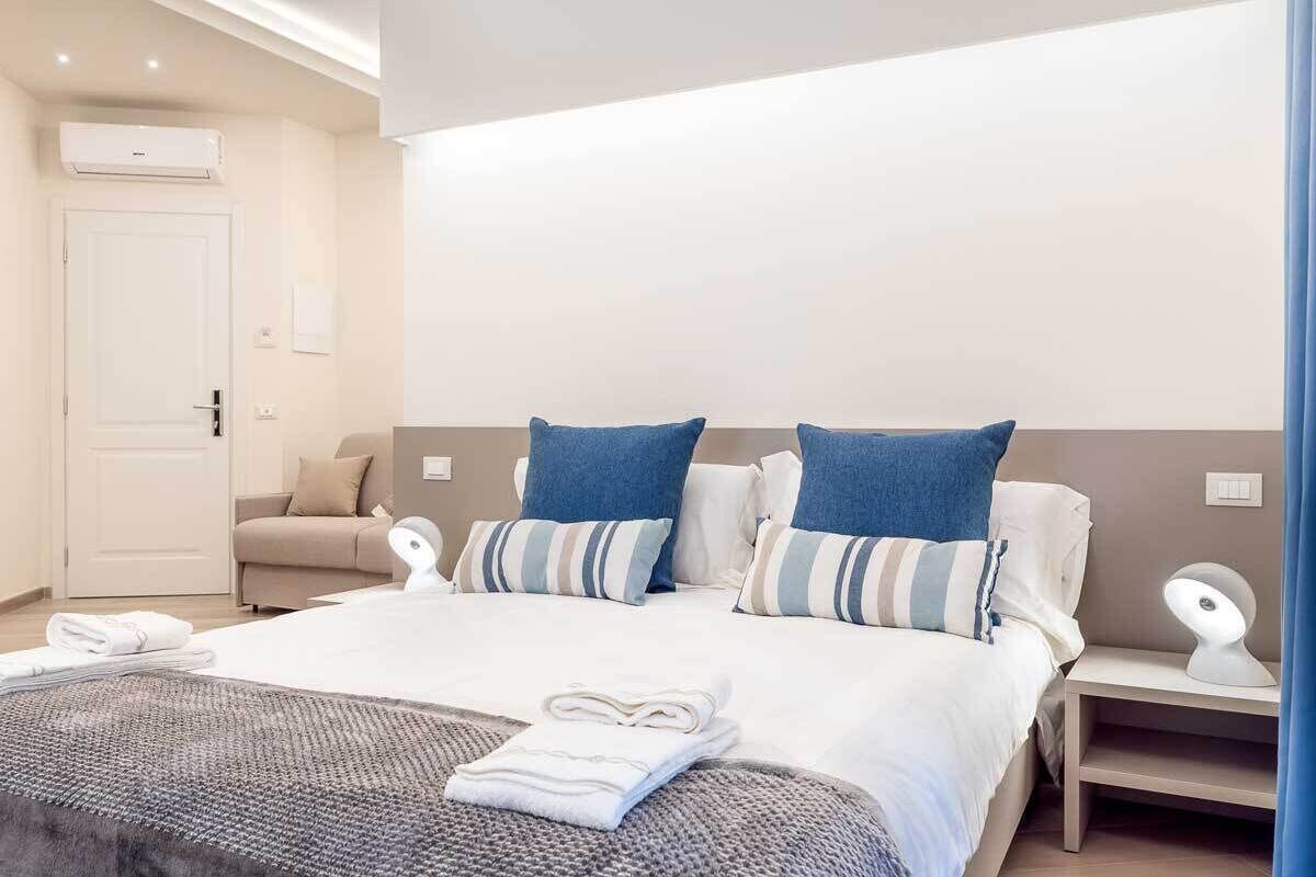 Une chambre d’hôtel avec un lit, une table de chevet, une lampe, un canapé et une porte.