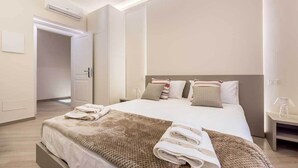 Een moderne hotelkamer met een groot bed, een nachtkastje en een airconditioning.