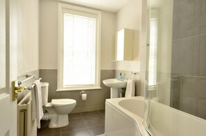 A modern bathroom with a toilet, sink, bathtub, and a glass shower enclosure. - Grosvenor House (Margate)