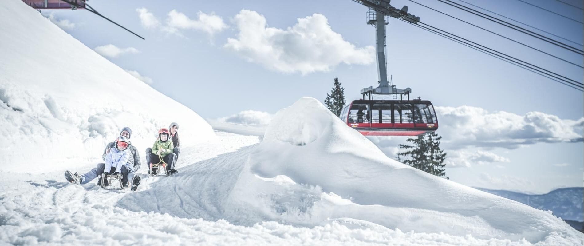 A ski lift with a cable car moving over a snowy mountain.