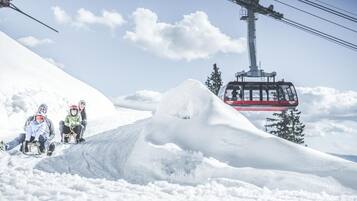 A ski lift with a cable car moving over a snowy mountain.