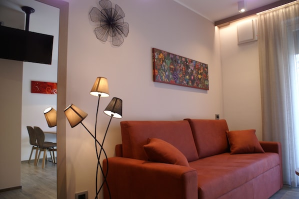 Una sala de estar moderna con un sofá, lámparas de pie y obras de arte en las paredes.