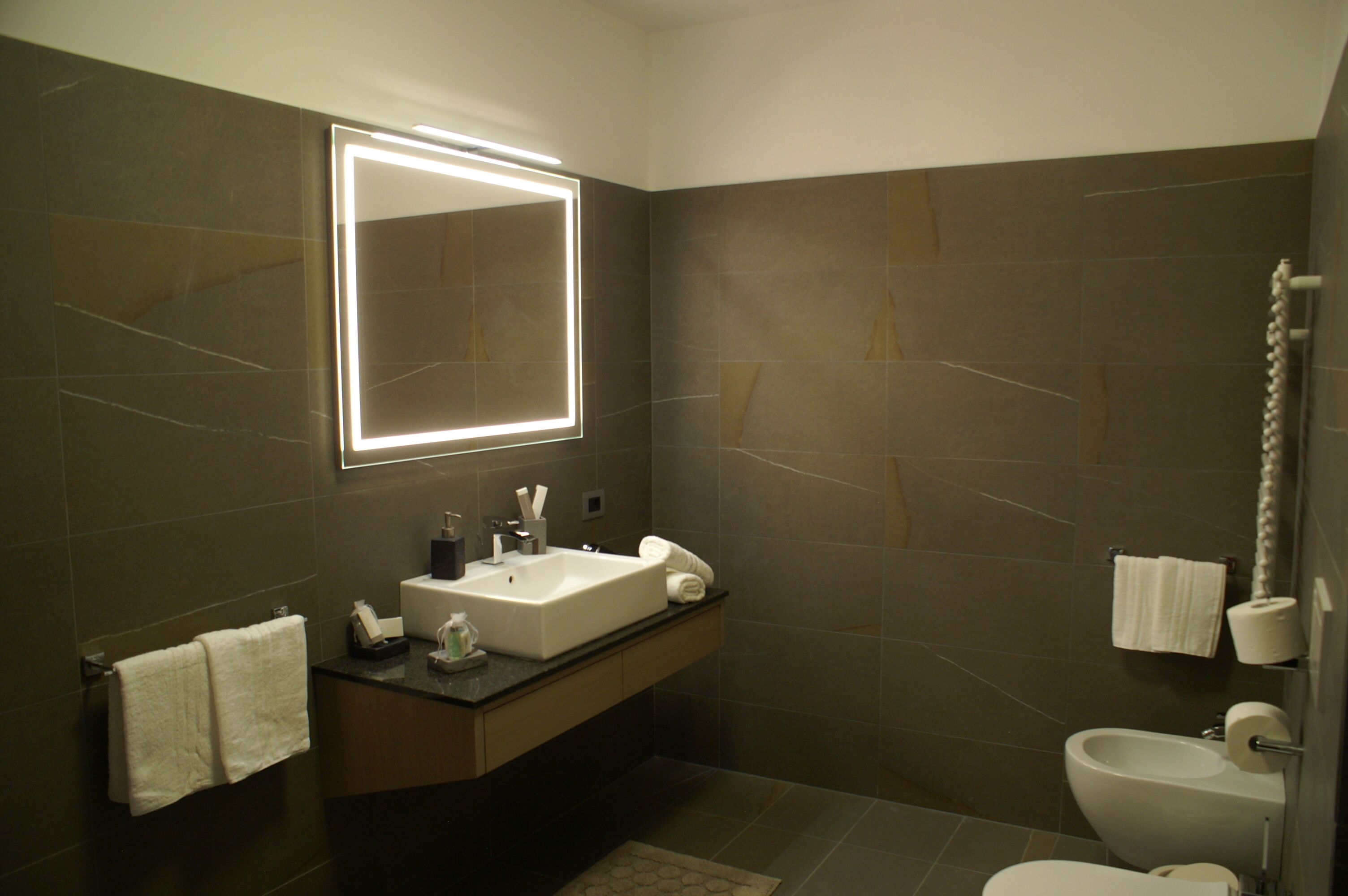A modern bathroom with a large mirror, a sink, a toilet, and a shower.