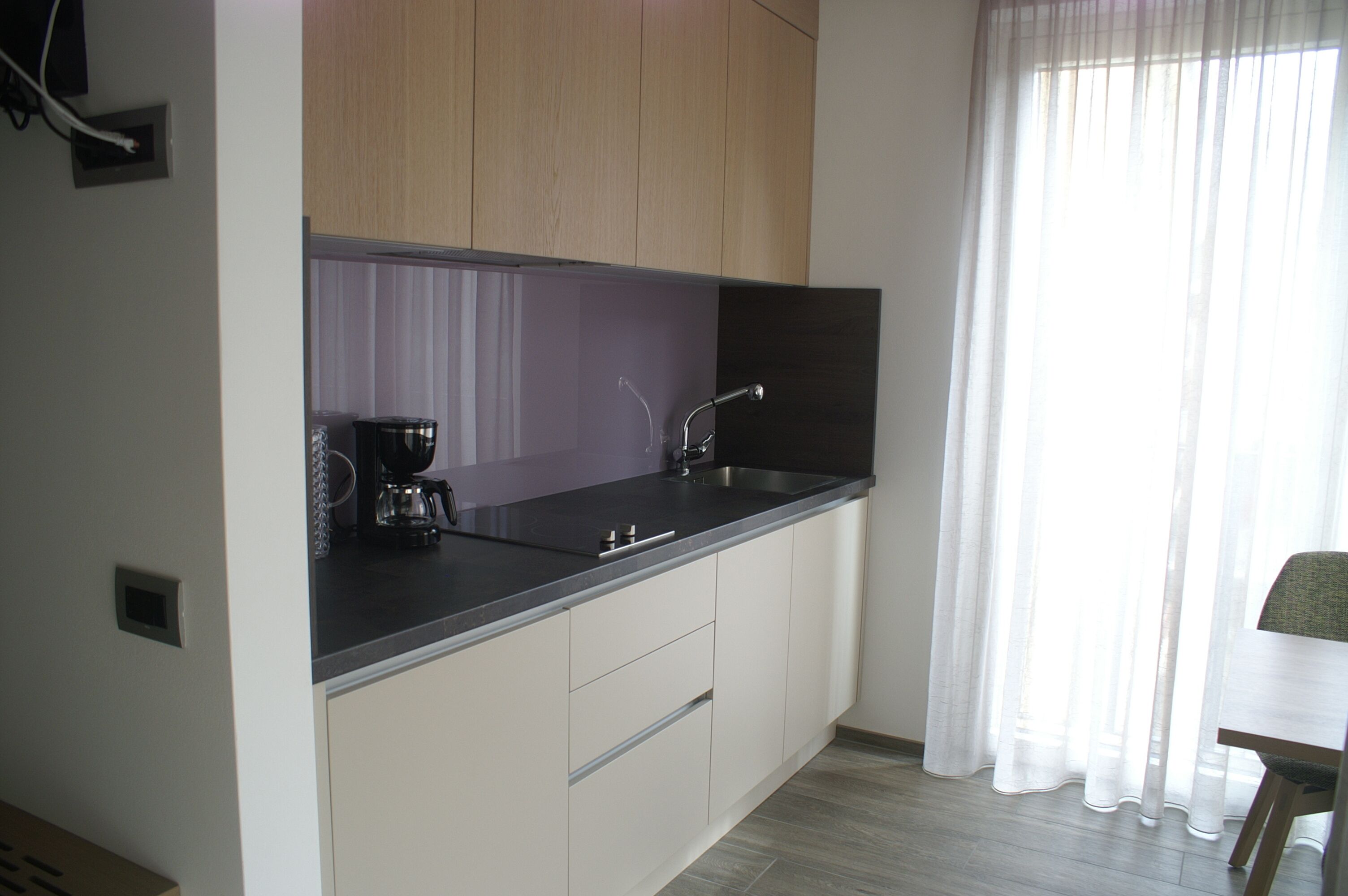 A modern kitchen with a black countertop, stainless steel sink, and white cabinets.