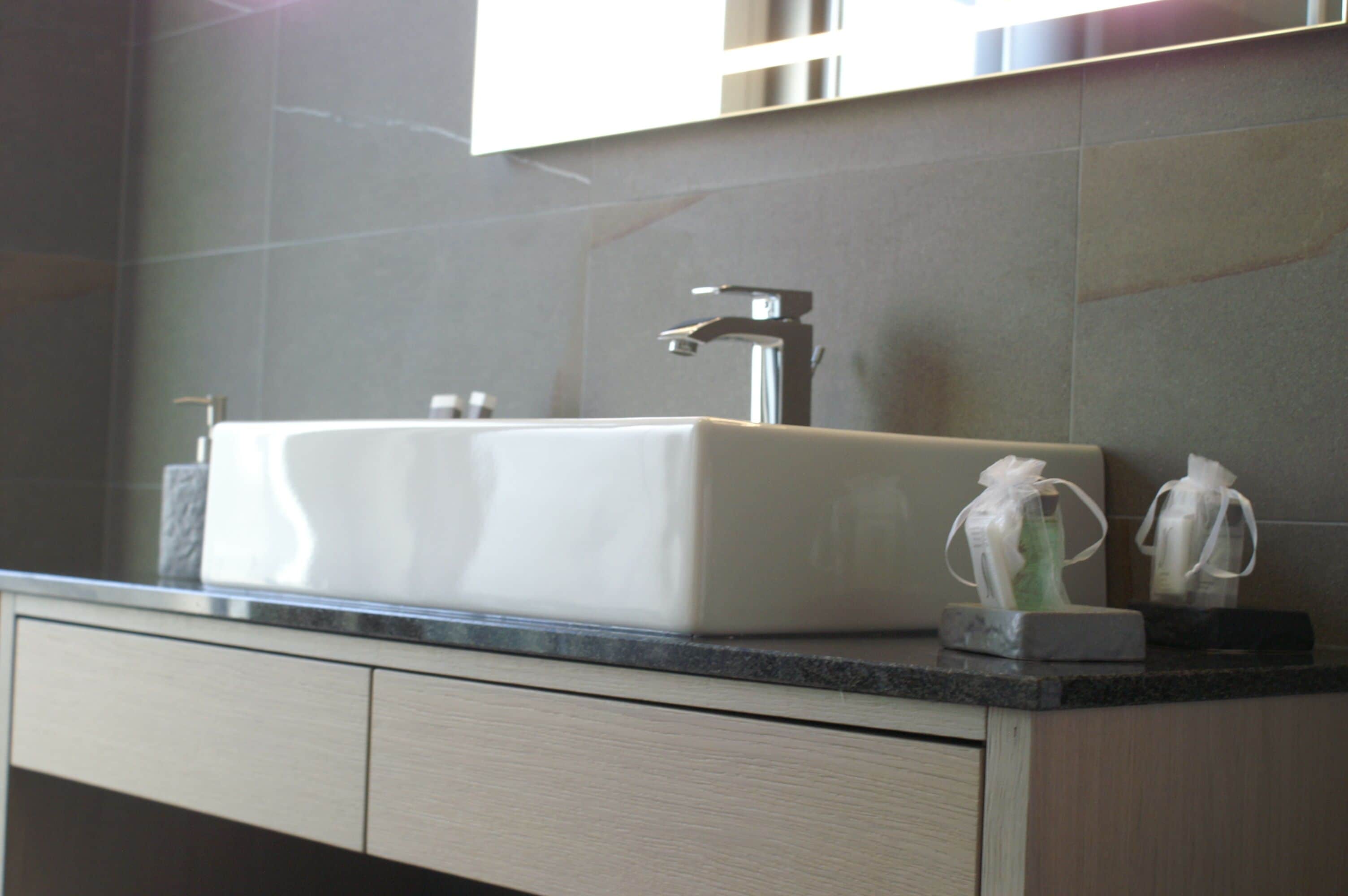 Un baño moderno con un lavabo rectangular, un grifo y dos dispensadores de jabón en la encimera.