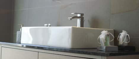 Een moderne badkamer met een rechthoekig wastafelblad, een kraan en twee zeepdispensers.