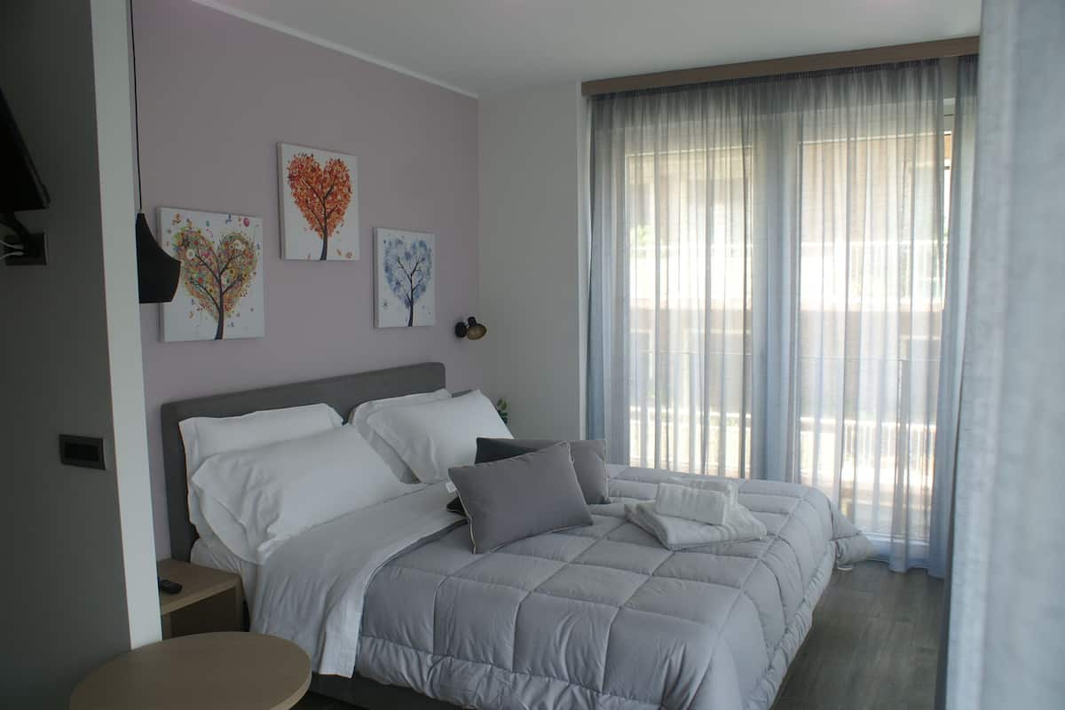 A bedroom with a bed, bedside tables, and artwork on the wall.