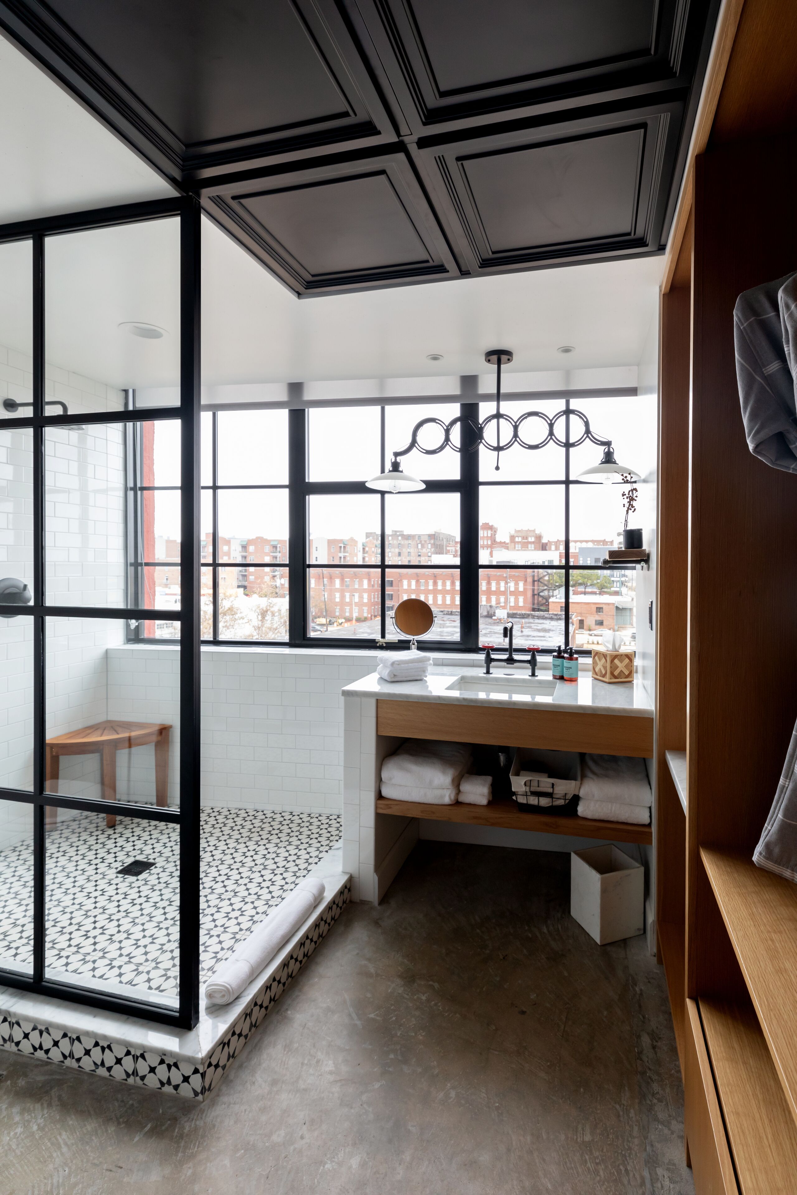 A modern bathroom with a large window, a shower area, and a vanity with a mirror.