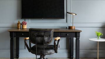 Un bureau moderne avec une chaise en cuir, un téléviseur à écran plat, une lampe et une petite table sur laquelle est posée une plante.