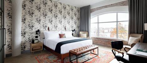 A bedroom with a large bed, a bench, a desk, and a chair.