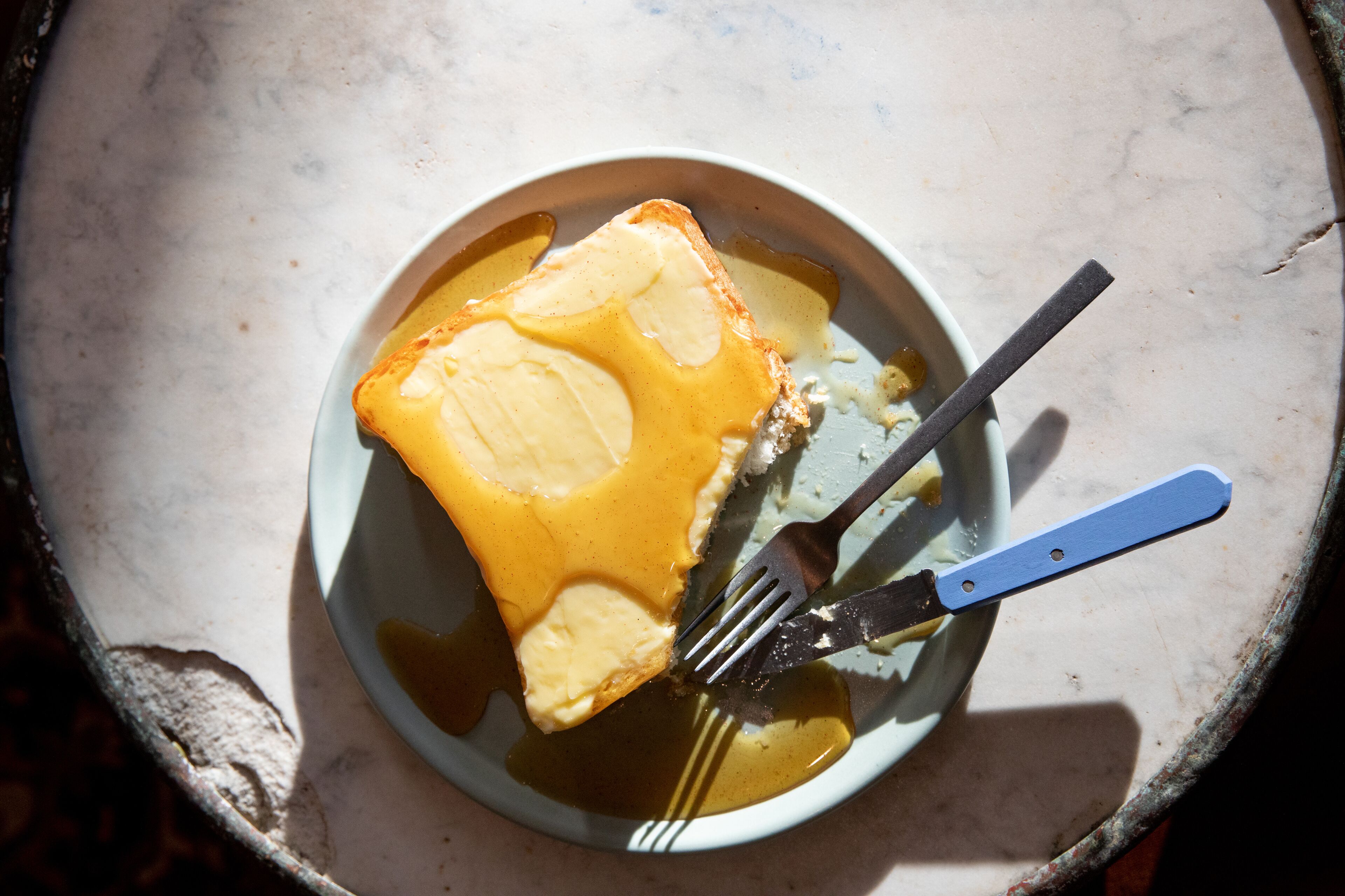 A plate with a slice of toast and a fork.