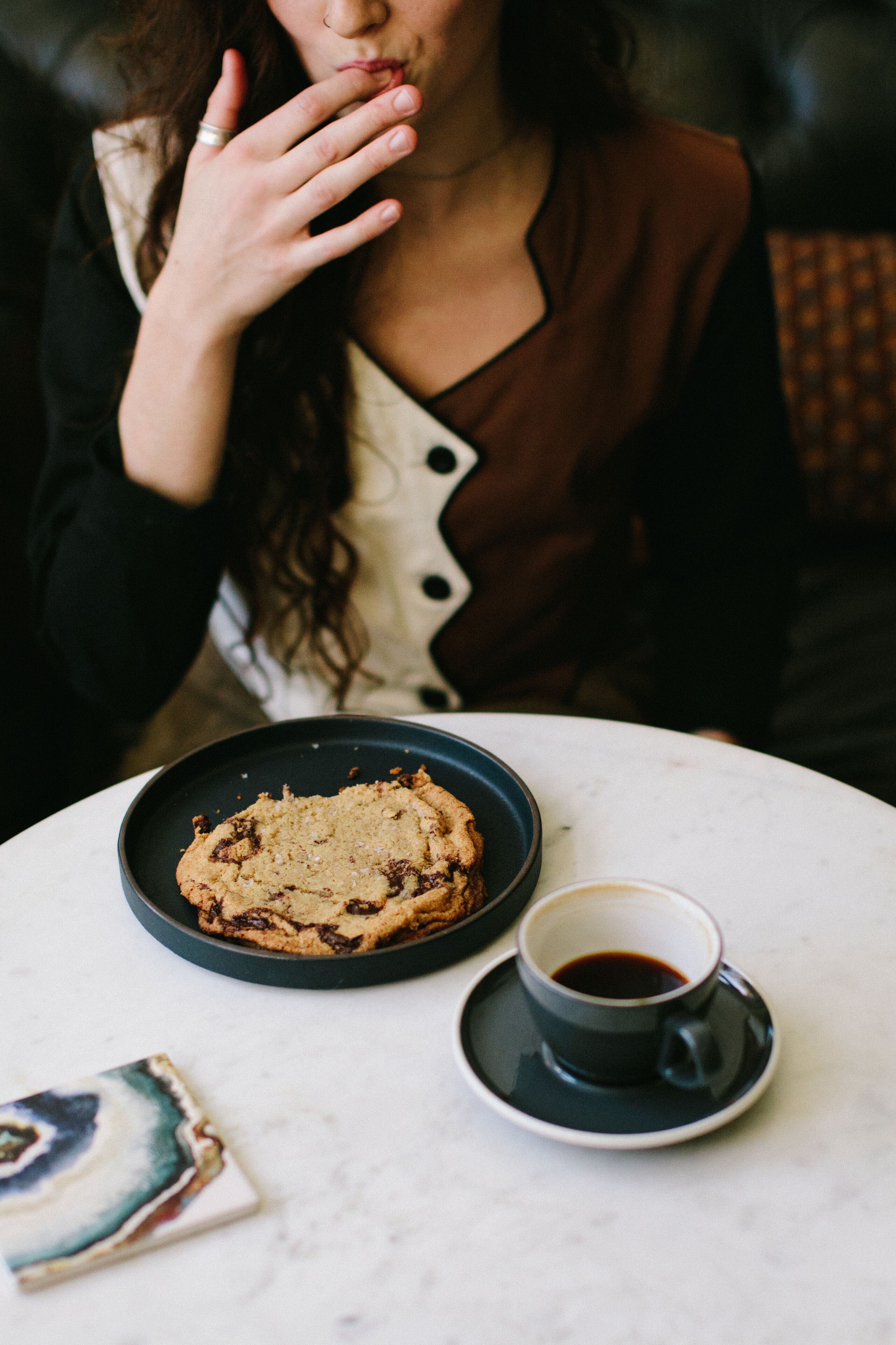 A person sitting at a table with a plate of cookies and a cup of coffee.
