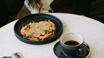 A person sitting at a table with a plate of cookies and a cup of coffee.