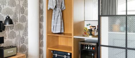 A room with a wooden wardrobe, a hanging robe, a radio, and a minibar.