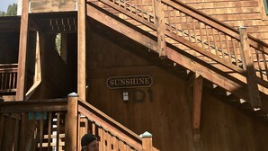 Ein Holzhaus mit Balkon und Treppe. Am Gebäude ist ein Schild mit der Aufschrift 'SUNSHINE'.