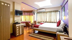 A hotel room with a bed, a desk, a chair, a television, and a window with curtains. - Hotel Shreesh (Port Blair)