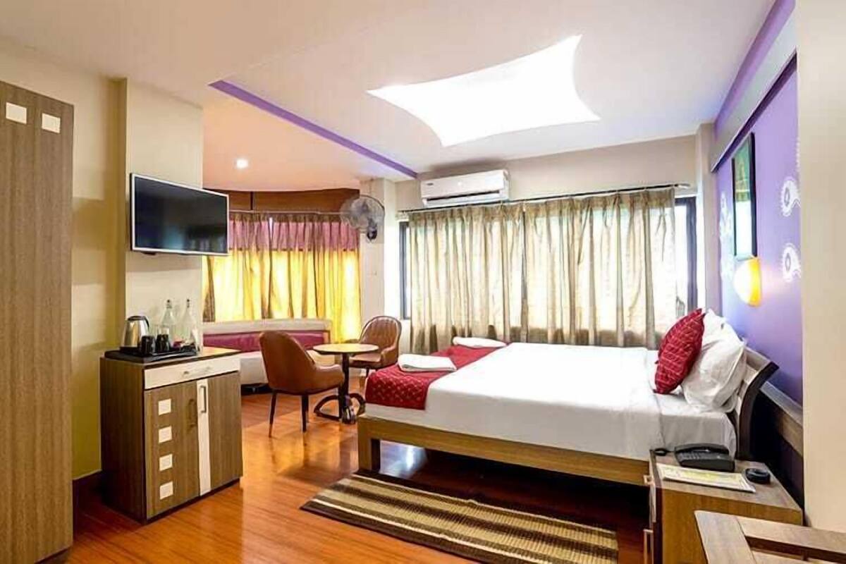 Une chambre d’hôtel équipée d’un lit, d’un bureau, d’une chaise, d’une télévision et d’une fenêtre avec des rideaux.