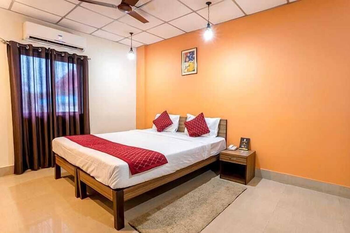 Une chambre à coucher avec un lit, des rideaux, une table de chevet et un ventilateur de plafond.