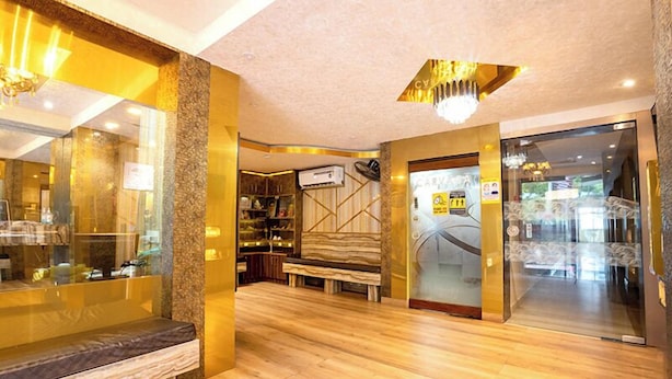 A hotel lobby with a wooden floor, a bench, a reception desk, and a glass door leading to the reception area. - Hotel Shreesh (Port Blair)