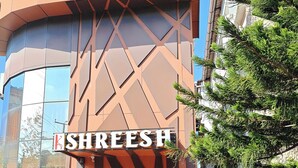 A hotel named 'ShreeSh' with a modern architectural design, a visible entrance, and potted plants around the entrance. - Hotel Shreesh (Port Blair)