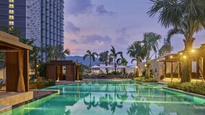 A swimming pool with a tiled surface, surrounded by palm trees and lounge chairs. - Hyatt Regency Shenzhen Yantian (Shenzhen)