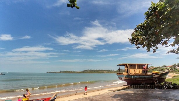 A wooden boat docked on a beach with a wooden walkway leading to it. - Paratibela Pousada (Anchieta)