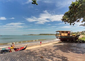 A wooden boat docked on a beach with a wooden walkway leading to it. - Paratibela Pousada (Anchieta)