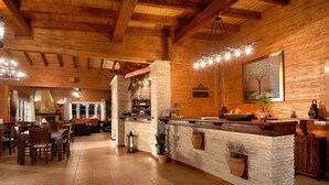 A rustic wooden interior with a stone bar, dining area, and a fireplace. - Villa Rustica (Konitsa)