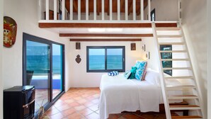 A bedroom with a bed, a staircase, a view of the ocean, and a microwave. - Casa Pata Salada (Sayulita)