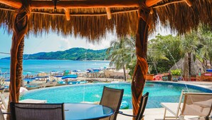 A poolside area with a view of the sea, lounge chairs, and umbrellas. - Casa Pata Salada (Sayulita)