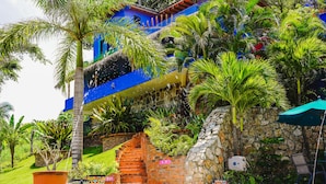 A vibrant blue building with a stone wall and a thatched roof structure. - Casa Pata Salada (Sayulita)