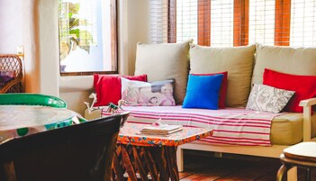 Un rincón acogedor con un sofá, almohadas y una mesa con libros y una cesta.