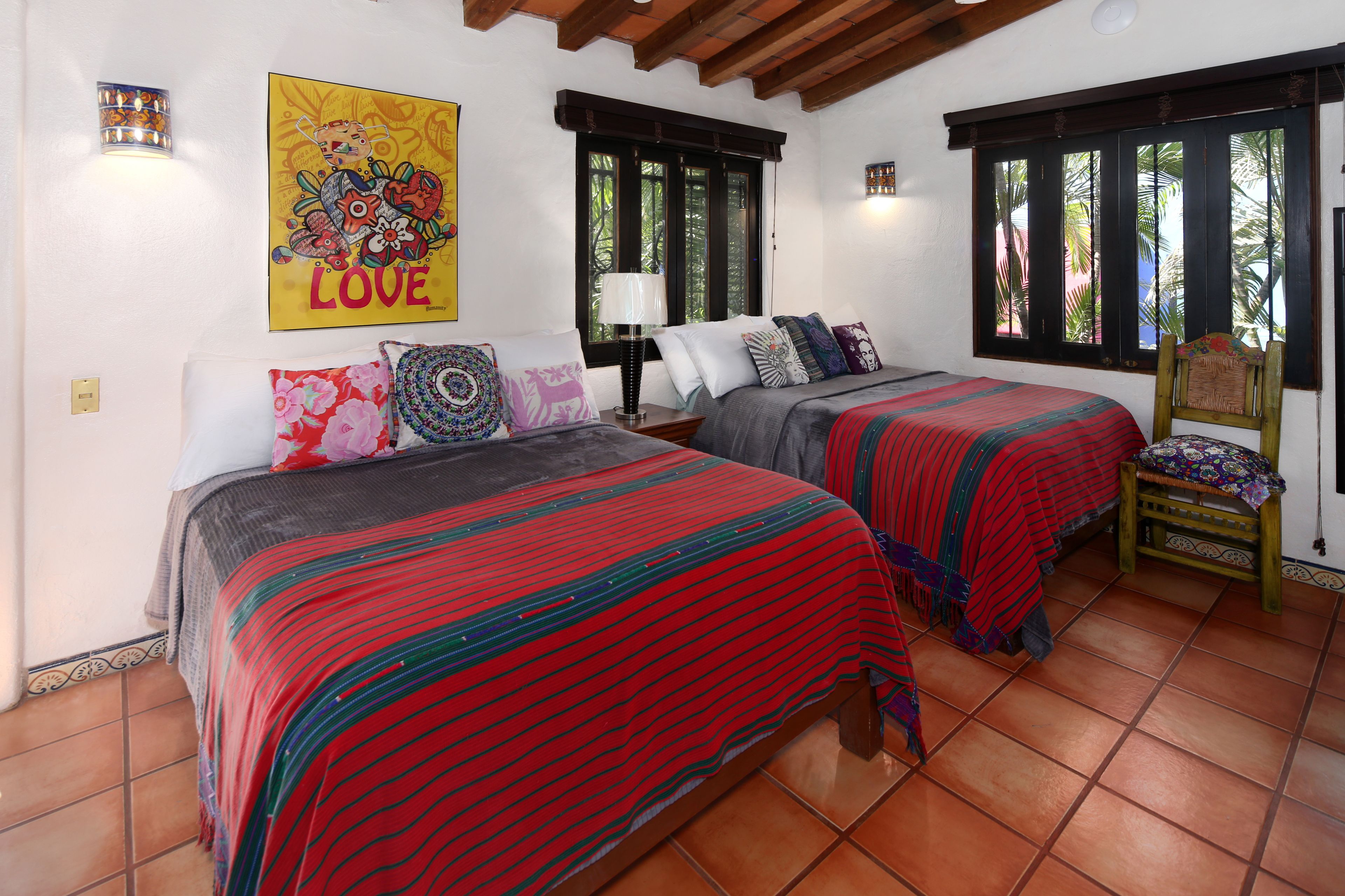 Un dormitorio con dos camas, una silla de madera y una pared con un cartel que dice 'LOVE'.