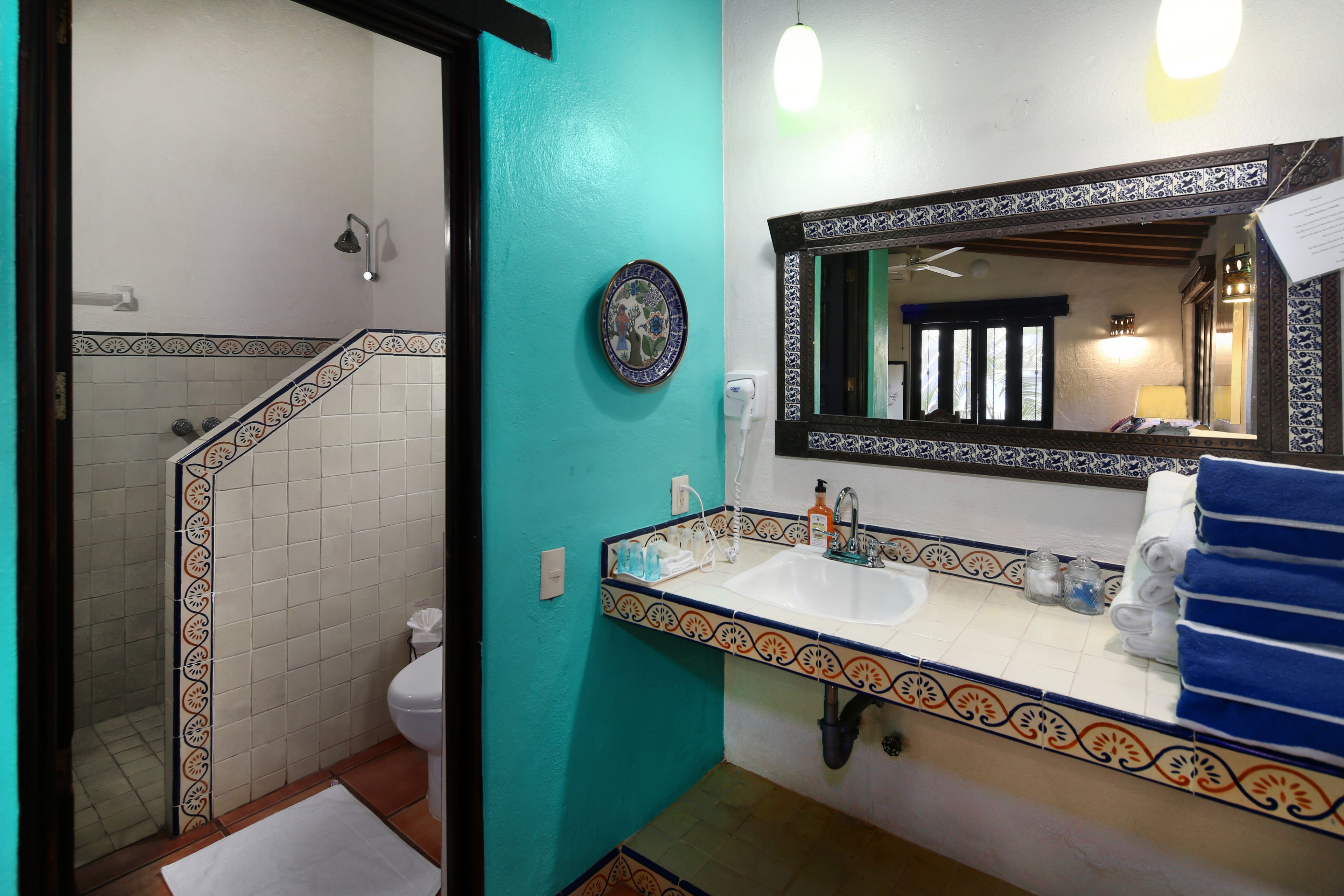Un baño con un lavabo blanco, un espejo con marco decorativo y un toallero azul.