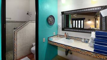 Un baño con un lavabo blanco, un espejo con marco decorativo y un toallero azul.