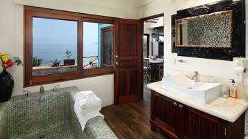 Un baño con un ventanal grande, una bañera, un lavabo y un espejo.