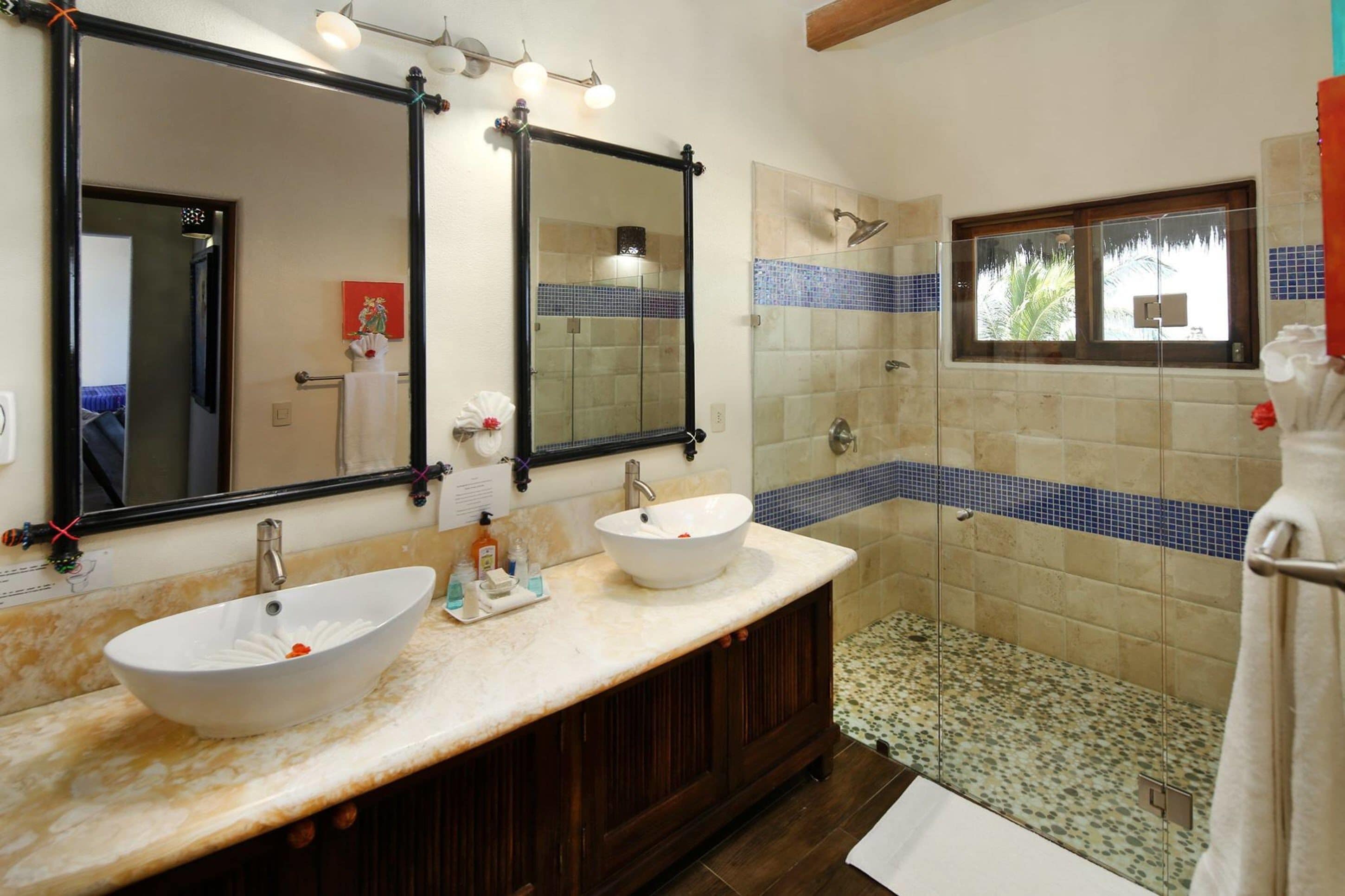 A bathroom with two sinks, a large mirror, and a shower area.