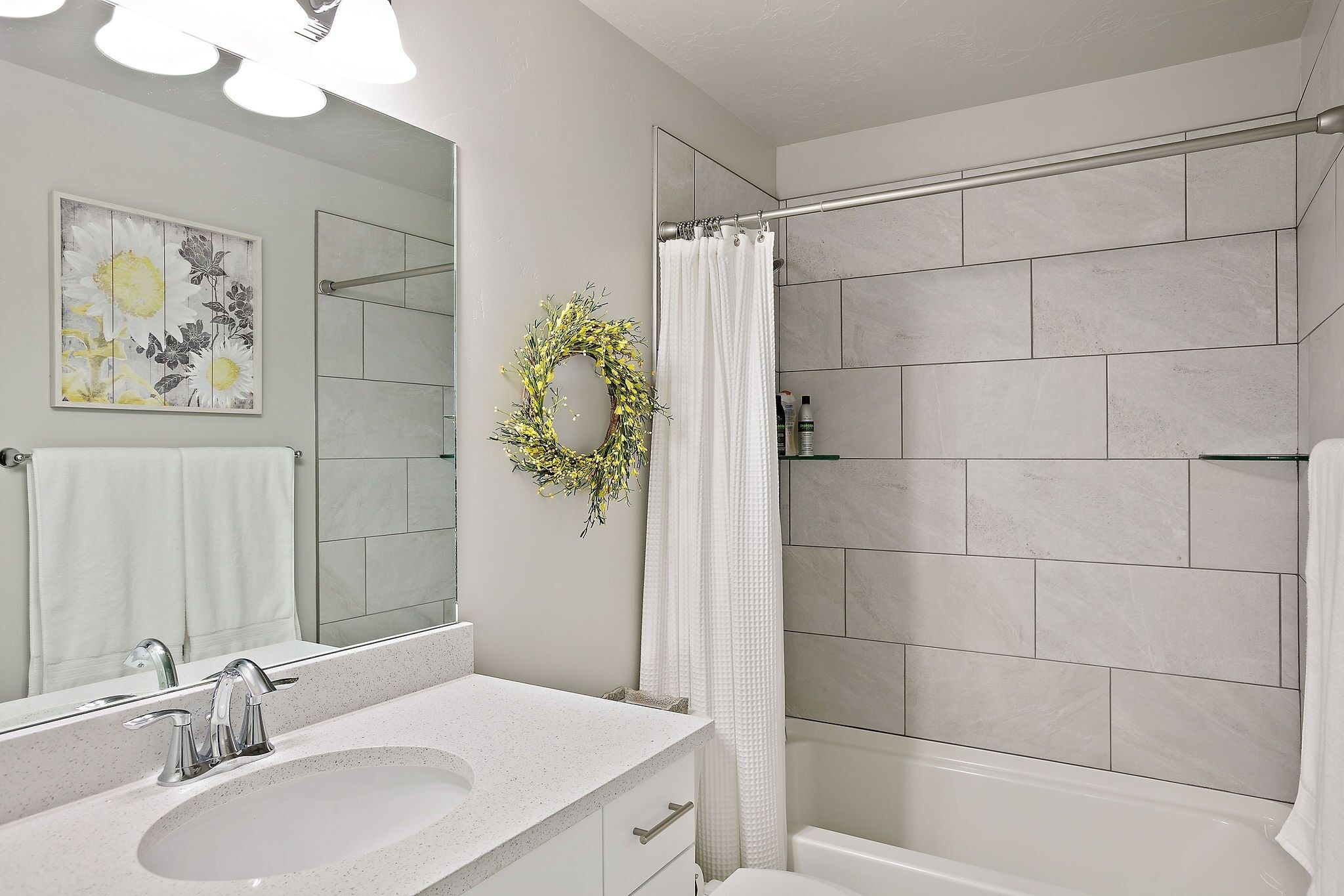 Un baño con lavamanos blanco, un espejo, cortina de ducha y un perchero de pared.