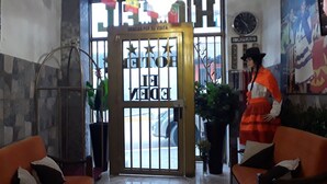 A hotel lobby with a large glass door, a clock on the wall, and orange seating. - Hotel El Eden de Adan y Eva (Andahuaylas)