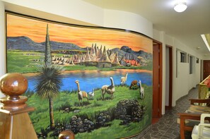Un couloir orné d’une grande fresque représentant un paysage avec des montagnes, un lac et divers animaux.