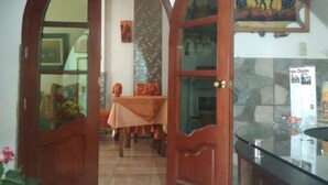 A room with a wooden door, a table with a tablecloth, and a glass partition. - Hotel El Eden de Adan y Eva (Andahuaylas)
