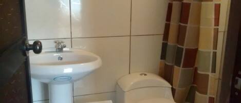 Un baño con lavamanos, inodoro y espejo blancos.
