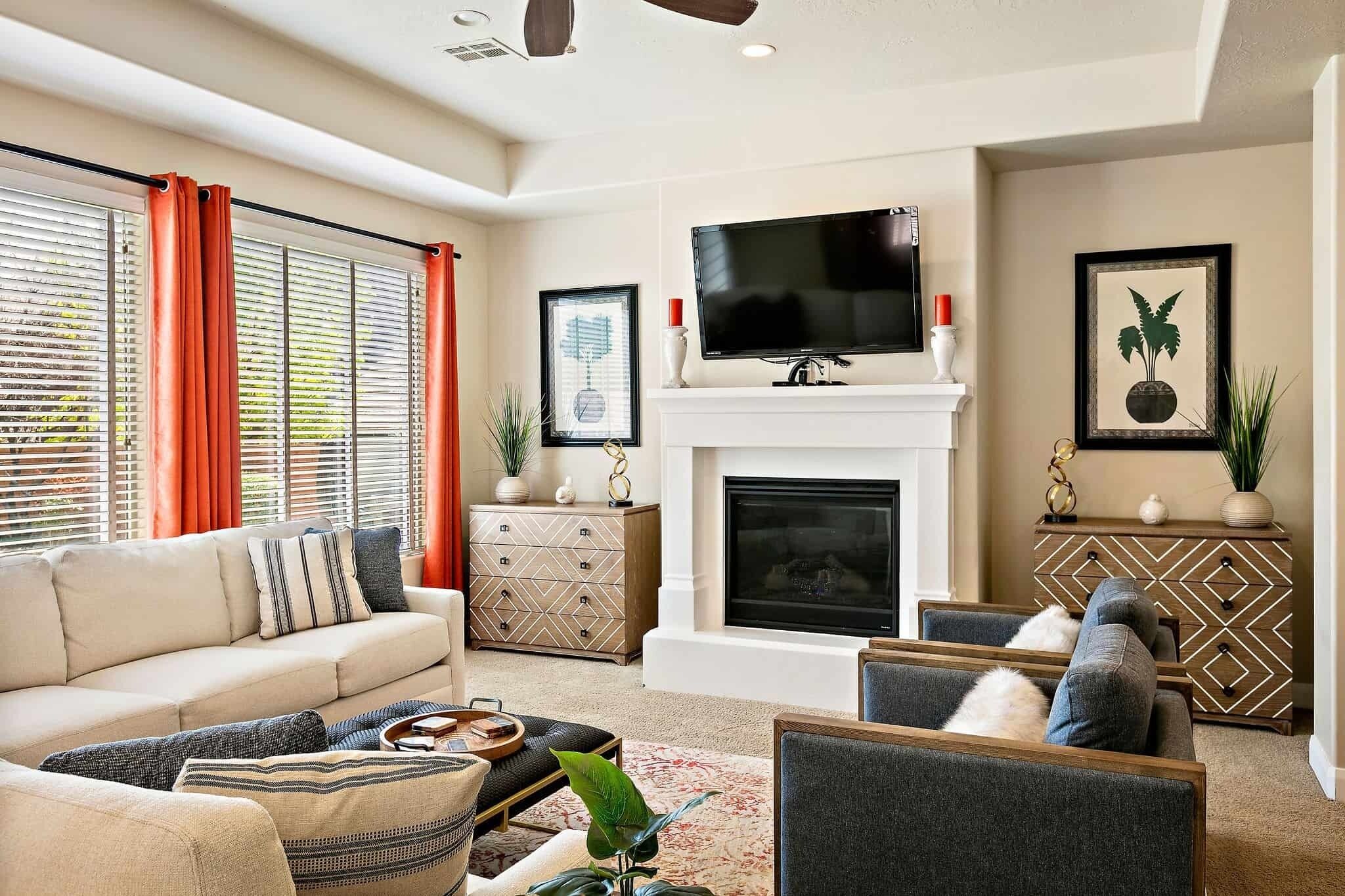 A living room with a sofa, armchairs, a fireplace, a TV, and decorative items.