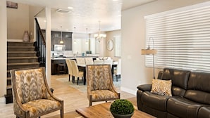 A modern living room with a sofa, two armchairs, a coffee table, and a staircase leading to a dining area. - Sunshine in Paradise #27 by RedAwning (Ivins)
