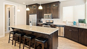 A modern kitchen with dark wood cabinets, stainless steel appliances, and a granite countertop. - Sunshine in Paradise #27 by RedAwning (Ivins)