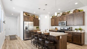 Une cuisine moderne avec des meubles en bois foncé, des appareils électroménagers en acier inoxydable et un îlot central doté de tabourets de bar.