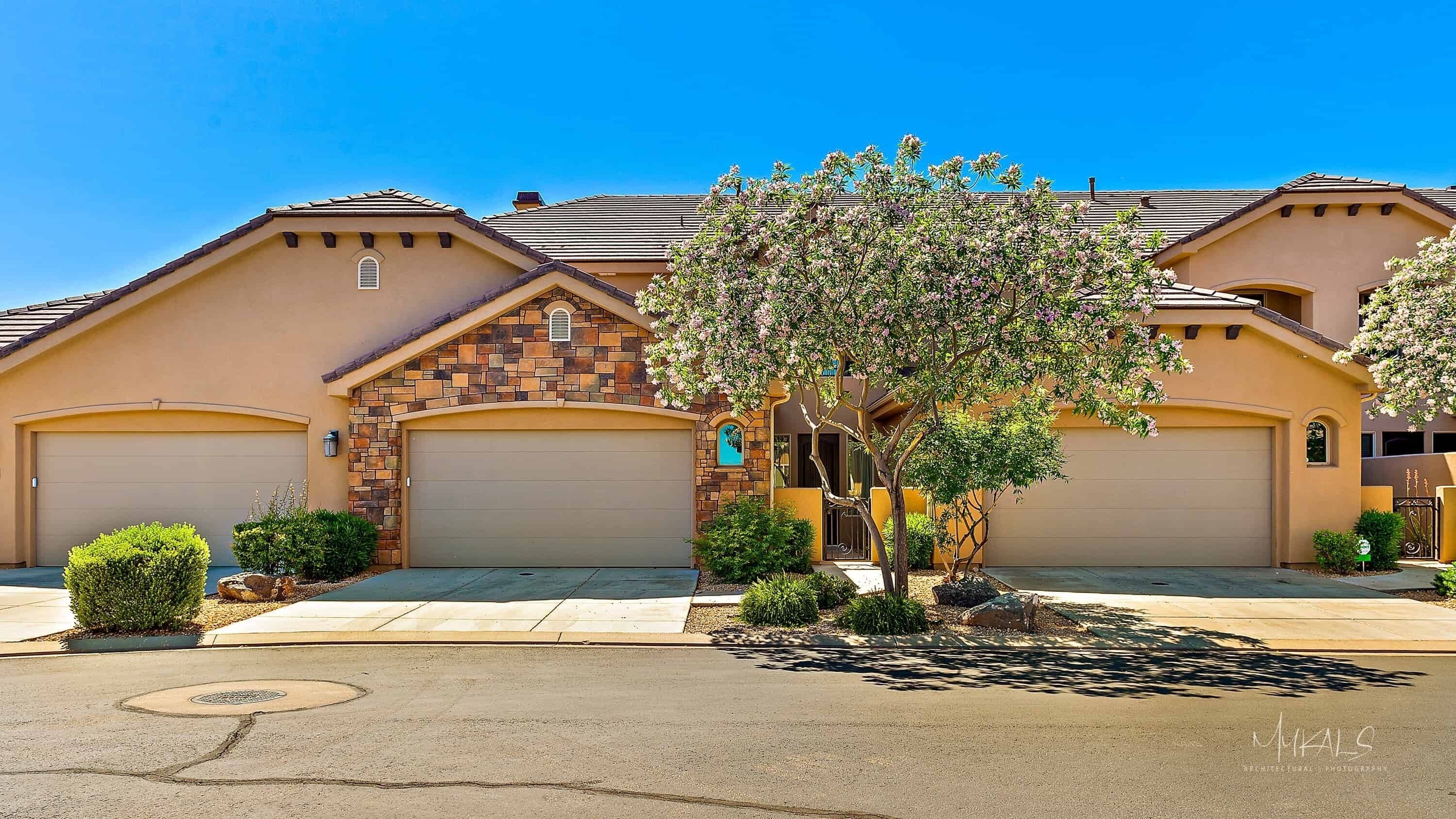 A two-story house with a stone facade, a garage, and a well-maintained front yard with a tree.