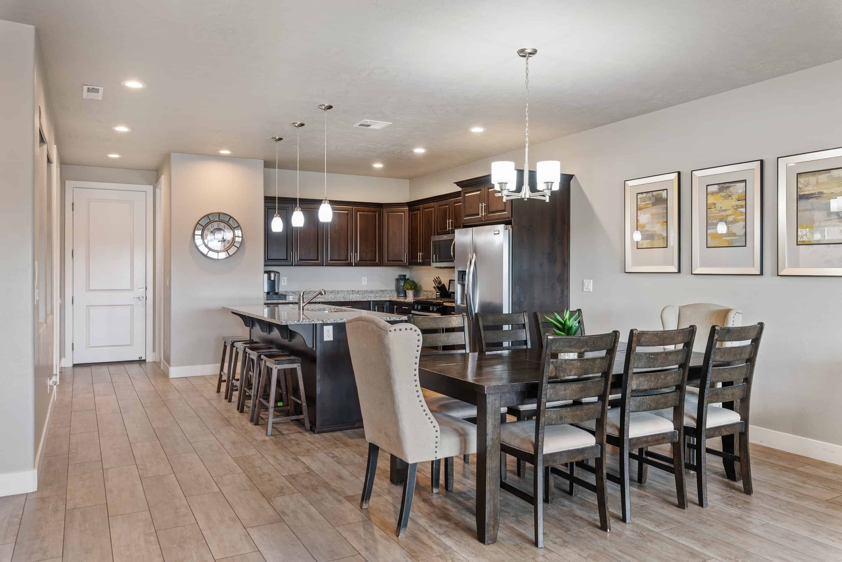 A modern kitchen with dark wooden cabinets, a central island, and a dining area with six chairs.