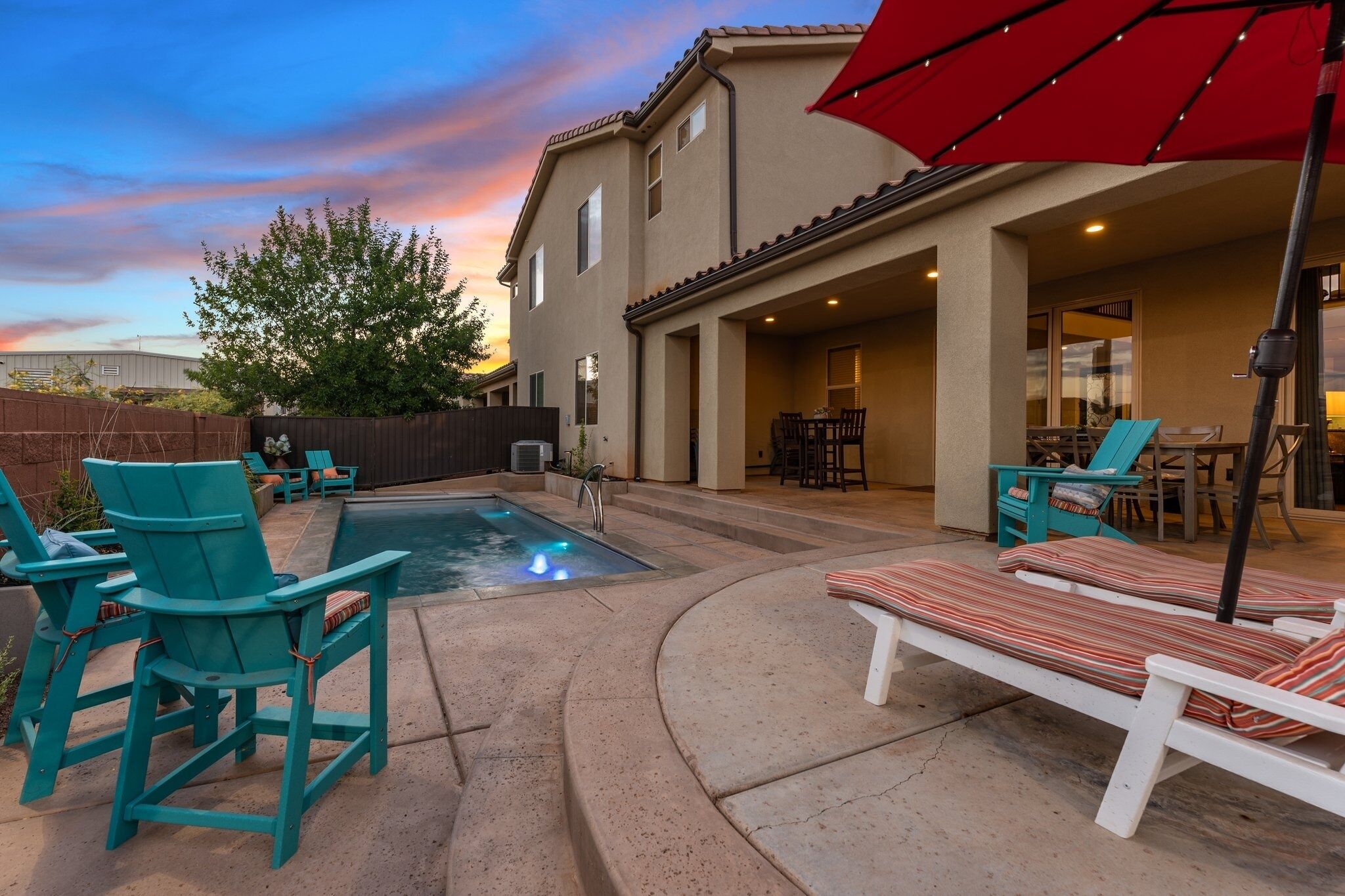 A backyard with a swimming pool, outdoor seating, and a covered patio area.
