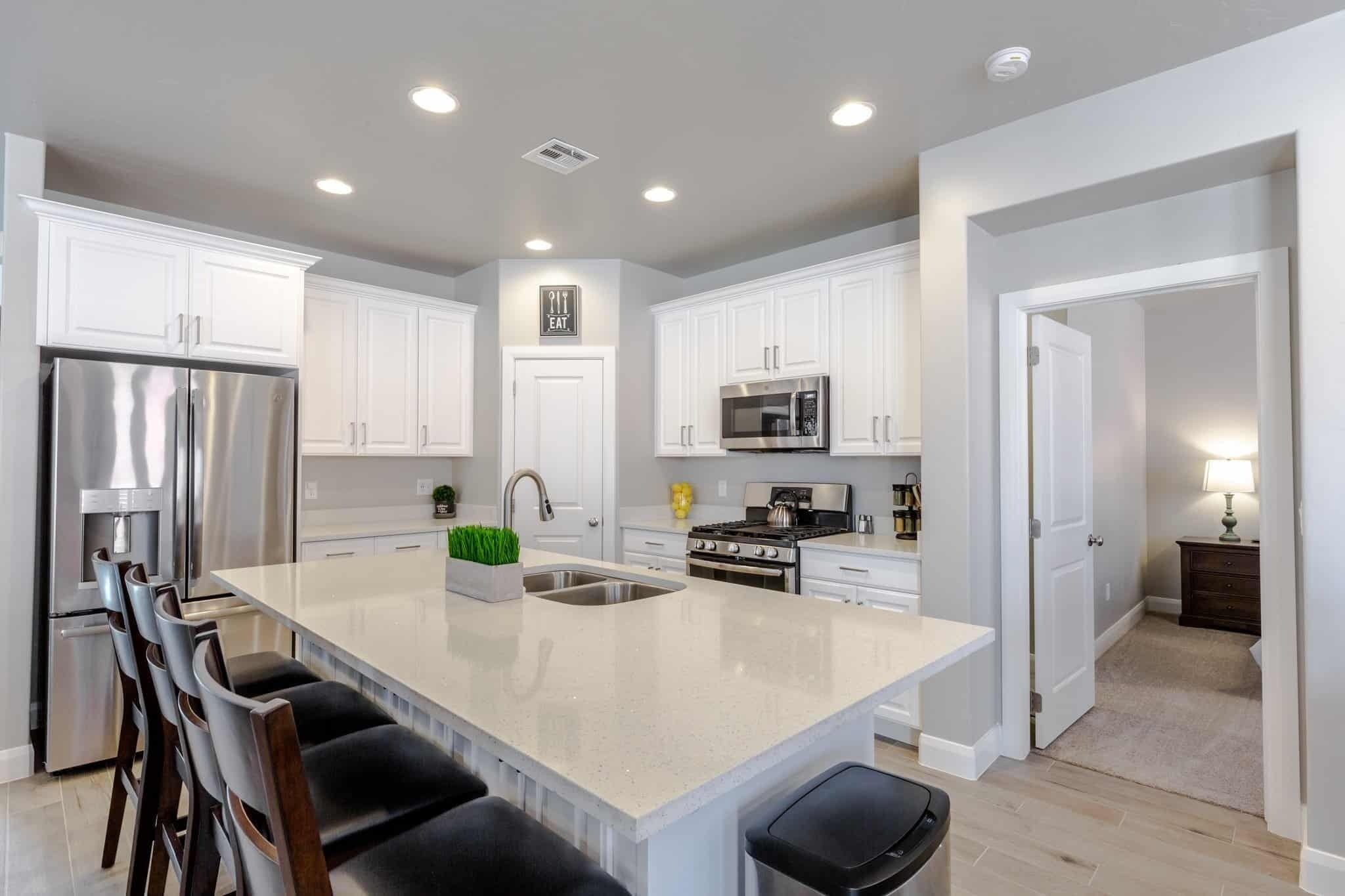 A modern kitchen with white cabinetry, stainless steel appliances, and a central island with seating.
